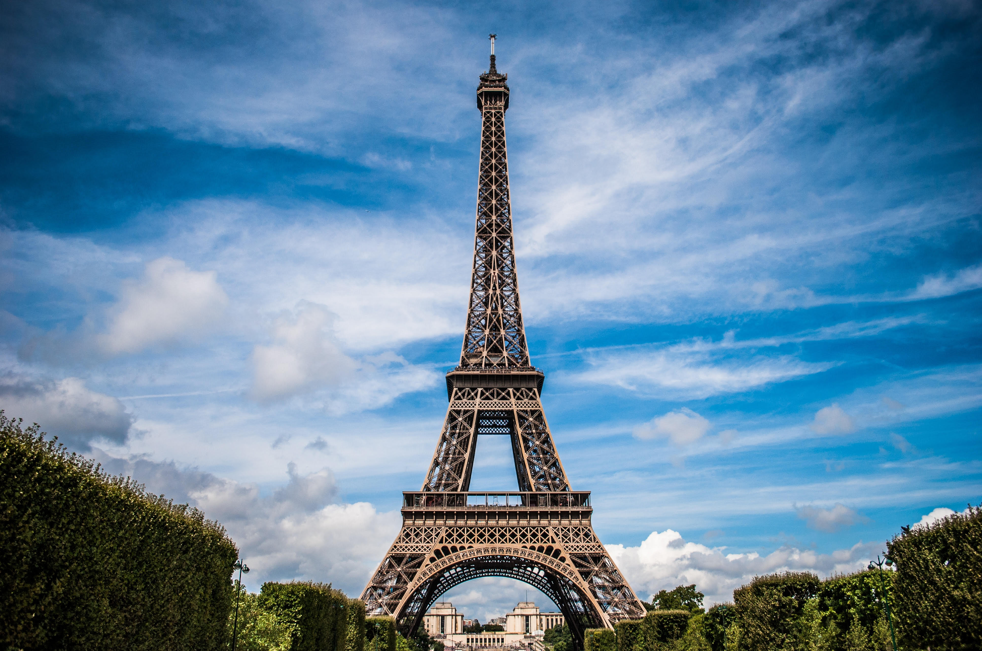The Eiffel Tower in Paris France stands tall against a bright blue but slightly cloudy sky